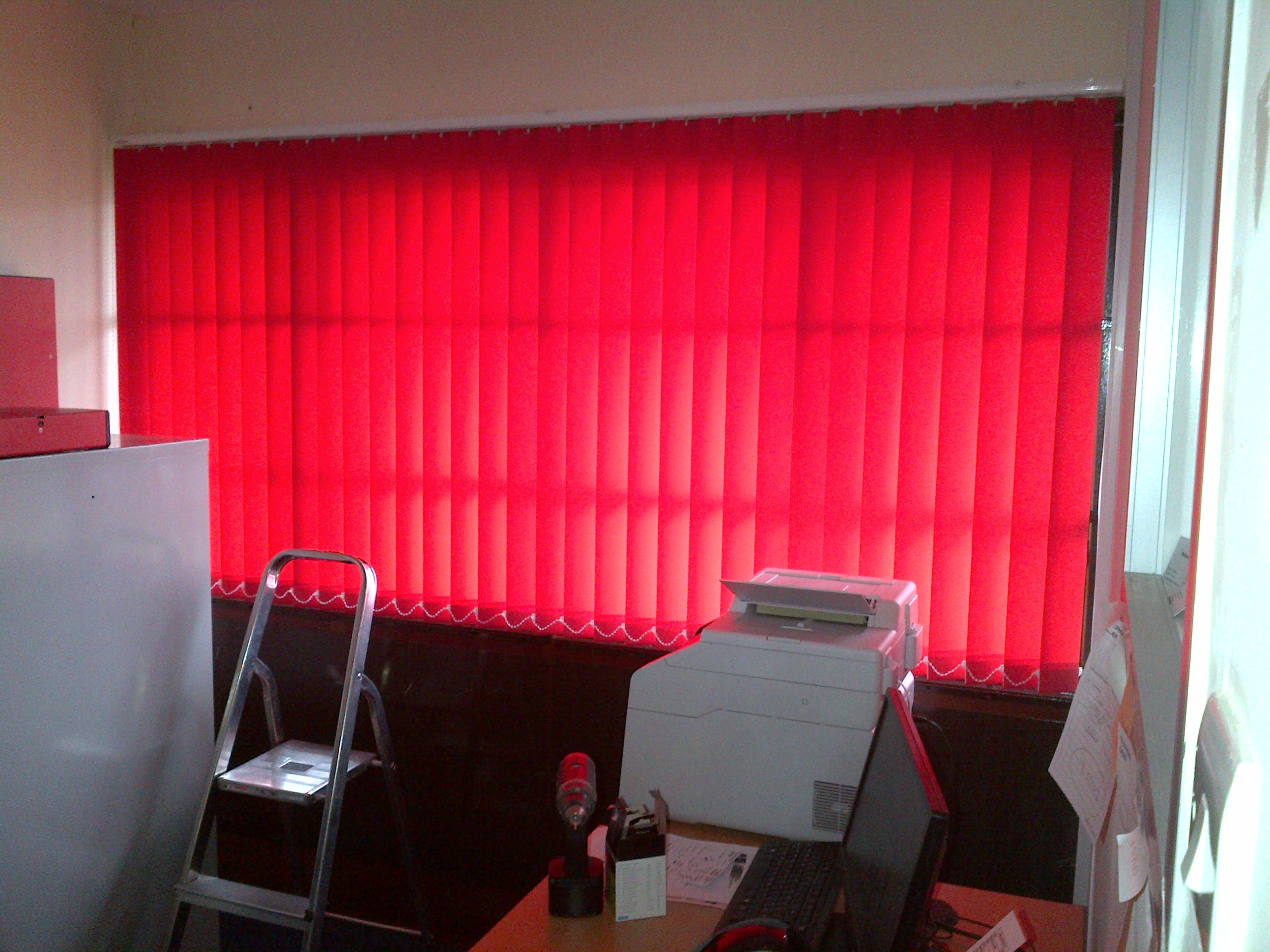 Bright red vertical blinds in truck parts showroom.